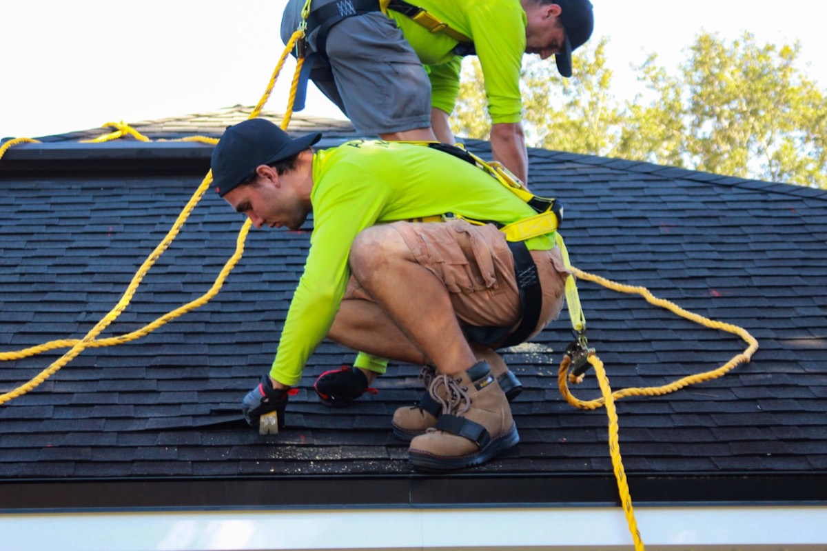 Crew tearing off old shingles during a full roof replacement
